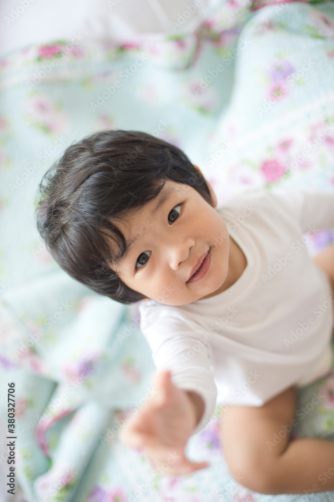 Boy sitting on bed looking up to camera
