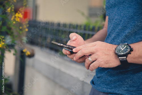 mans hands and cellphone reading emails and texting in a garden working from a garden 