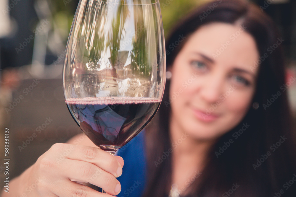 woman drinking a large glass of red wine outside in a garden backyard  in the continental in naples old town florida 