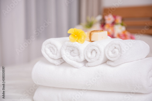 White towels,soap,candle and beautiful frangipani or plumeria flowers in bamboo wooden basket on modern white bedroom