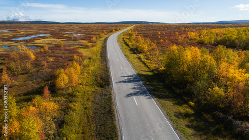 Aerial view of road and forest in autumn colors. Highway to Lapland. Beautiful landscape with rural road and trees with colorful leaves. Ruska fall season in Finland.