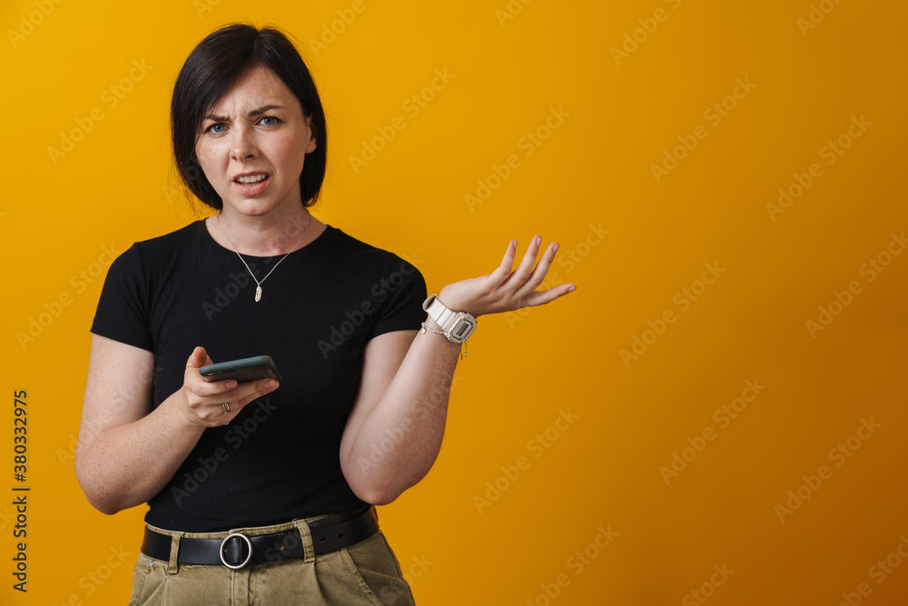 Confused young woman holding mobile phone