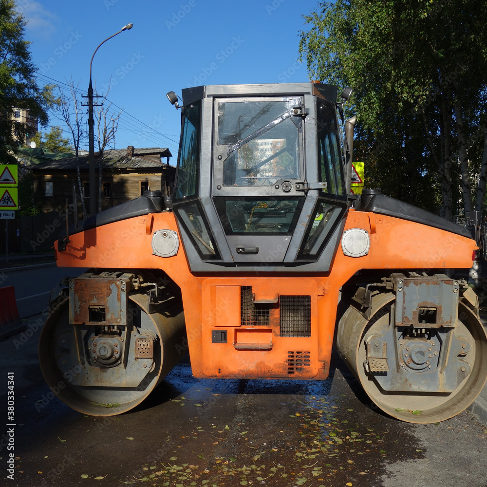 Repair of urban roads, asphalt roller on an autumn day against the background of the city, road construction machines. road construction concept. Repair of urban roads, asphalt roller on an autumn day against the background of the city, road construction machines. road construction concept.