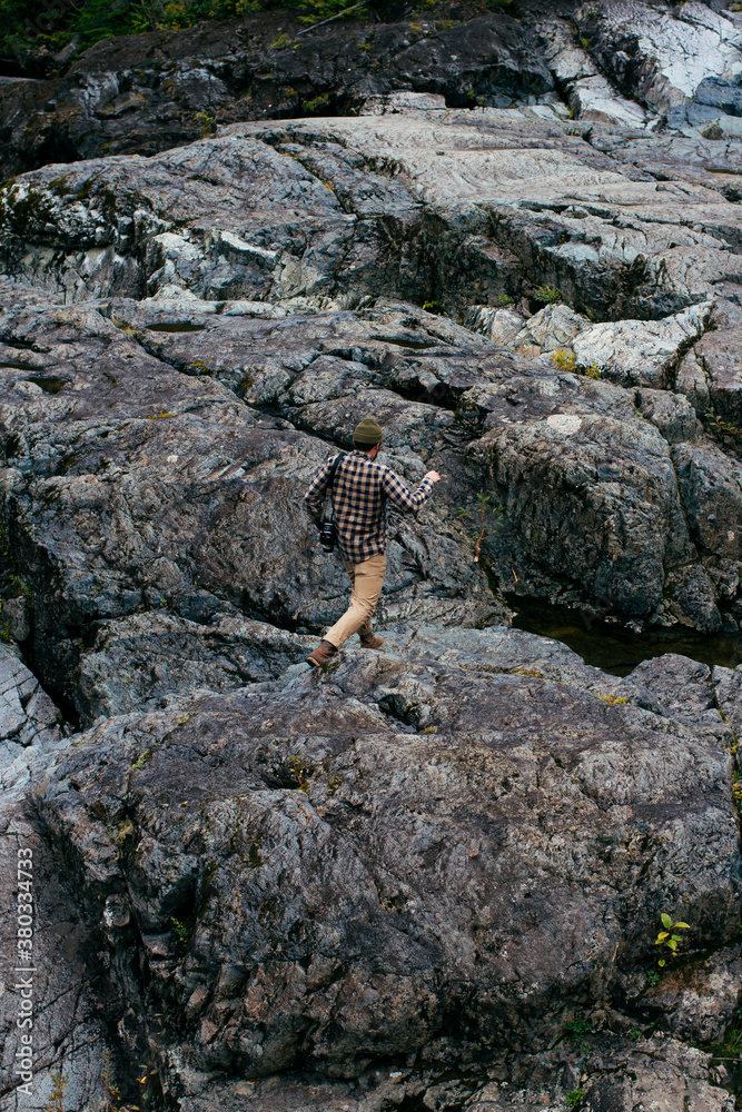 young man on rocks by river young man on rocks by river
