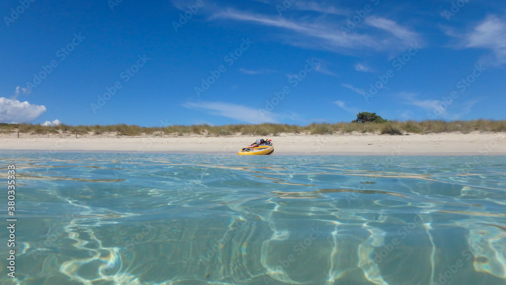Obraz premium A paddle surf board in the shore of a beach in the mediterranean sea with turquoise water and blue sky. Summer fun activity.