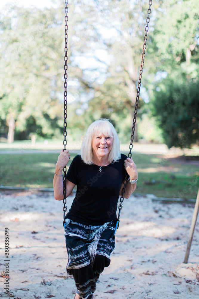 Smiling senior woman sitting on a swing Smiling senior woman sitting on a swing