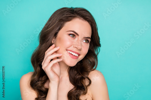 Closeup photo of beautiful cheerful lady curly hairstyle smiling positive touch cheek perfect smooth skin spa salon procedure feel good look mirror nude isolated bright teal color background