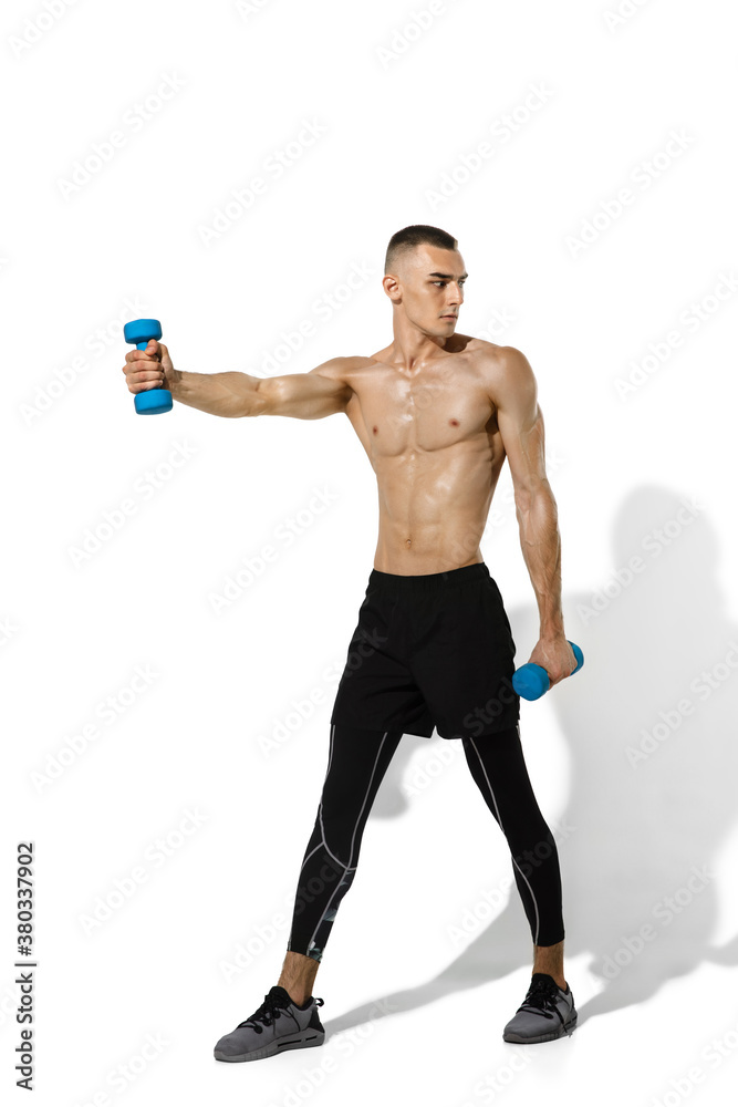 Weights. Stylish young male athlete practicing on white studio background, portrait with shadows. Sportive fit model in works out in motion and action. Body building, healthy lifestyle, style concept. Weights. Stylish young male athlete practicing on white studio background, portrait with shadows. Sportive fit model in works out in motion and action. Body building, healthy lifestyle, style concept.