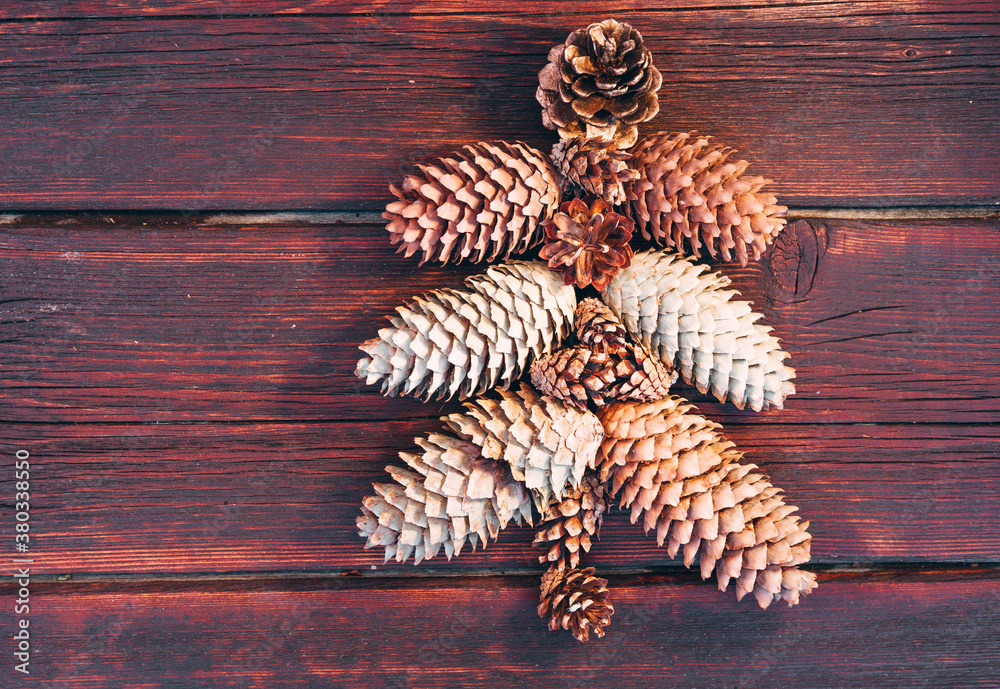 Beautiful wooden Christmas background. Happy new year and merry Christmas. The pine tree is laid out on a brown wooden background. Christmas tree made of cones. Beautiful wooden Christmas background. Happy new year and merry Christmas. The pine tree is laid out on a brown wooden background. Christmas tree made of cones.