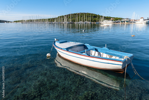 Fototapeta Naklejka Na Ścianę i Meble -  Wooden fishing boat and its reflection in the clear water in the bay in the Adriatic sea in Rogoznica, Croatia
