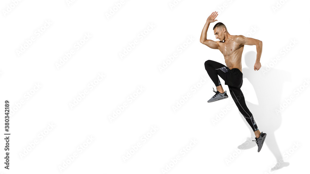 Running, jumping. Stylish young male athlete on white studio background, portrait with shadows. Sportive fit model in motion and action. Body building, healthy lifestyle, style concept. Flyer