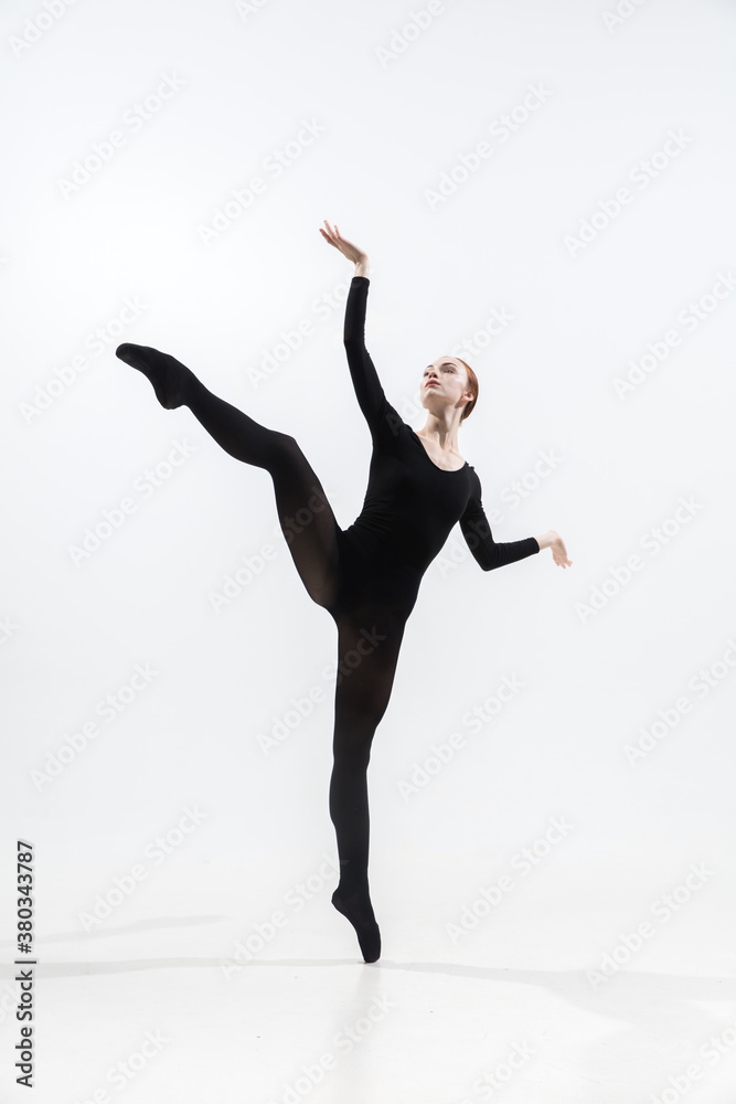 Weightless. Young and graceful ballet dancer in minimal black style isolated on white studio background. Art, motion, action, flexibility, inspiration concept. Flexible caucasian ballet dancer.