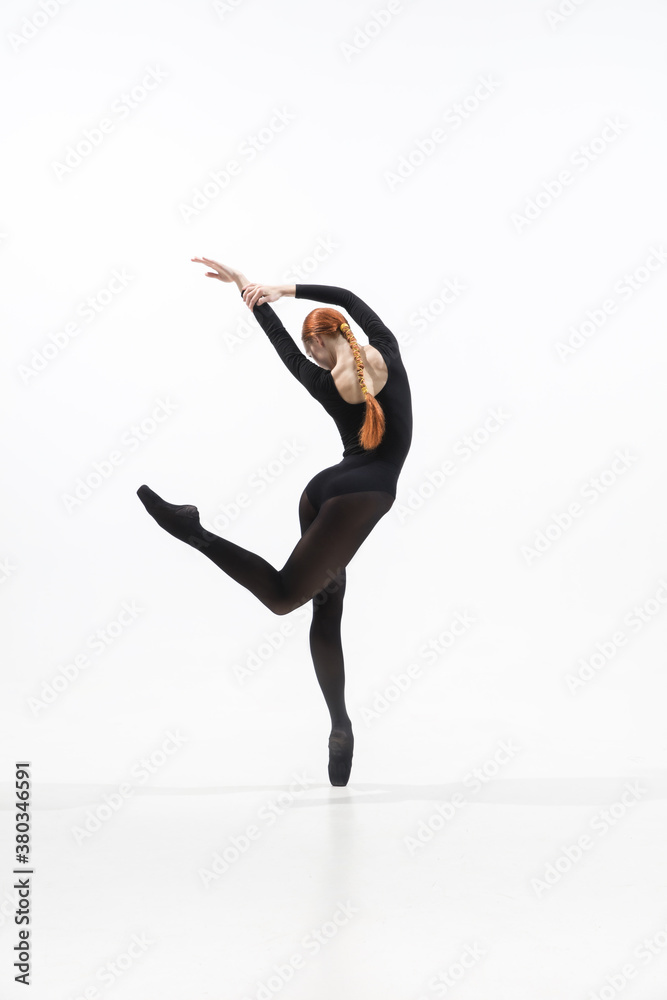 Light. Young and graceful ballet dancer in minimal black style isolated on white studio background. Art, motion, action, flexibility, inspiration concept. Flexible caucasian ballet dancer.