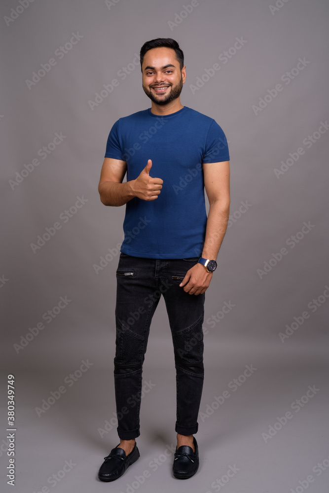 Young bearded Indian man against gray background Young bearded Indian man against gray background