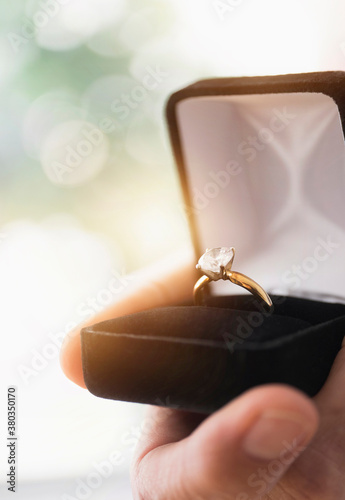 Close up of man's hand holding open box with engagement ring