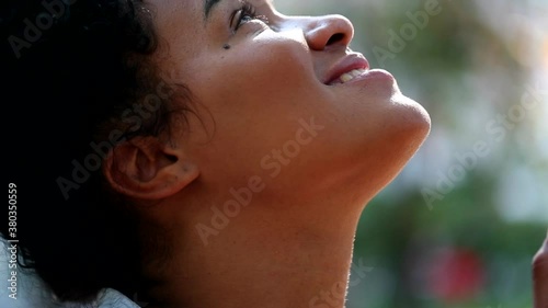 African woman worshiping outside, looking up to sky with faith photo