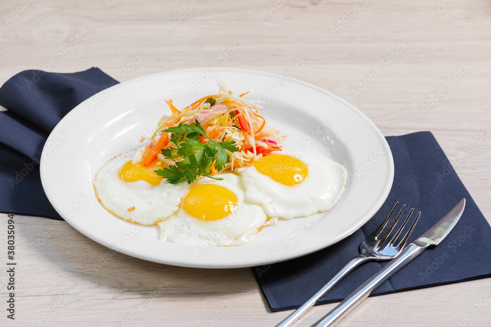 Breakfast of fried eggs, salad of fresh vegetables are on a white plate and a light background. Concept healthy food. Breakfast of fried eggs, salad of fresh vegetables are on a white plate and a light background. Concept healthy food.