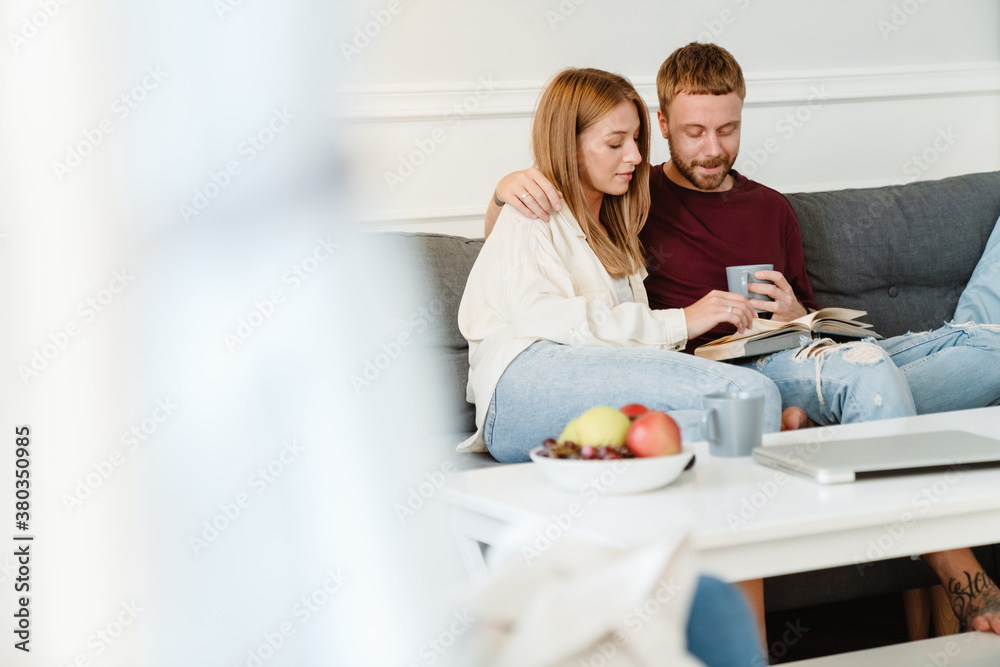 Image of ginger happy couple drinking coffee and reading book