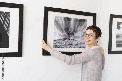Woman hanging photographs in art gallery