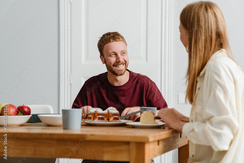 Photo of joyful beautiful couple talking while drinking tea with pie Photo of joyful beautiful couple talking while drinking tea with pie