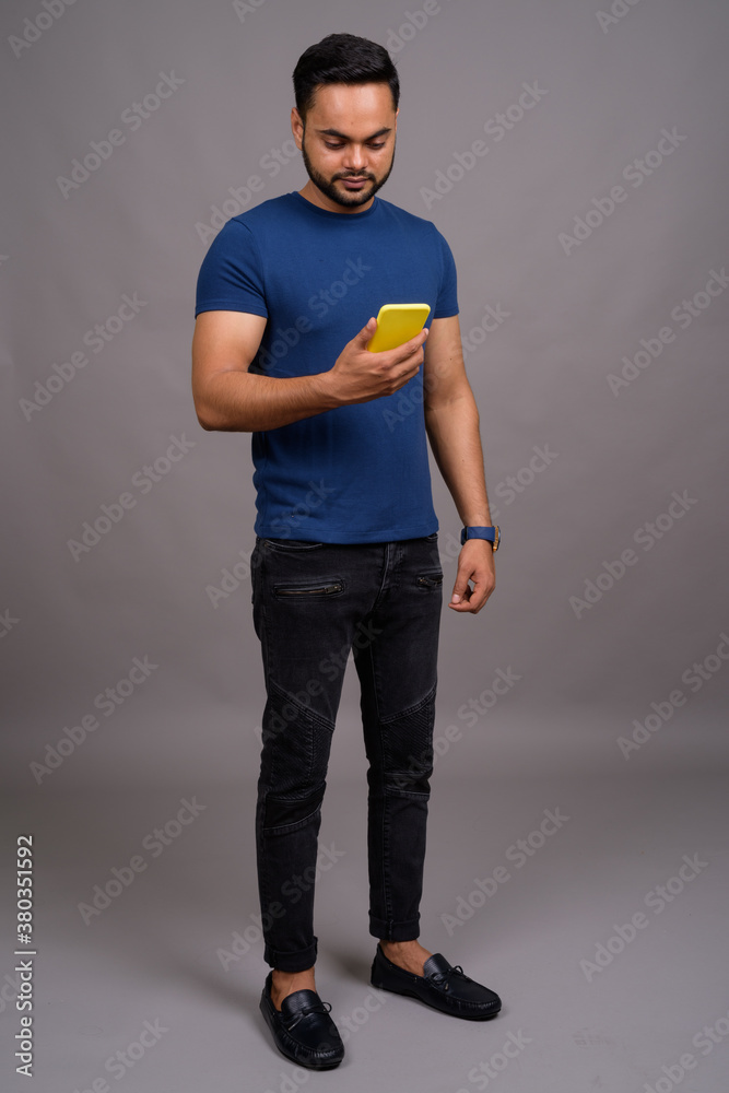 Young bearded Indian man against gray background Young bearded Indian man against gray background