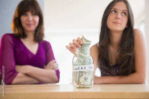 Teenage girl (14-15) putting money in swear jar