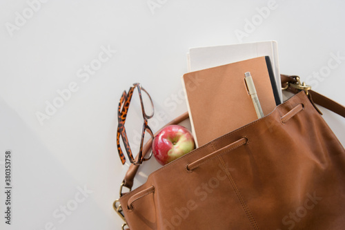 Studio Shot of shoulder bag with apple and notebook in it