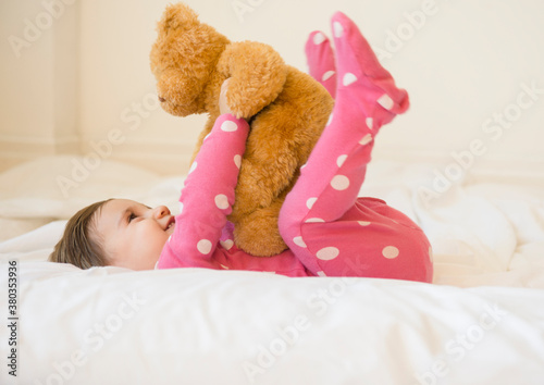 Girl (2-3) lying on bed with teddy bear photo