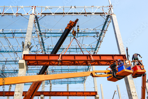 Construction workers installation steel structure girder runway beam lifting by mobile crane and placing on corbel of column concrete at the construction site project