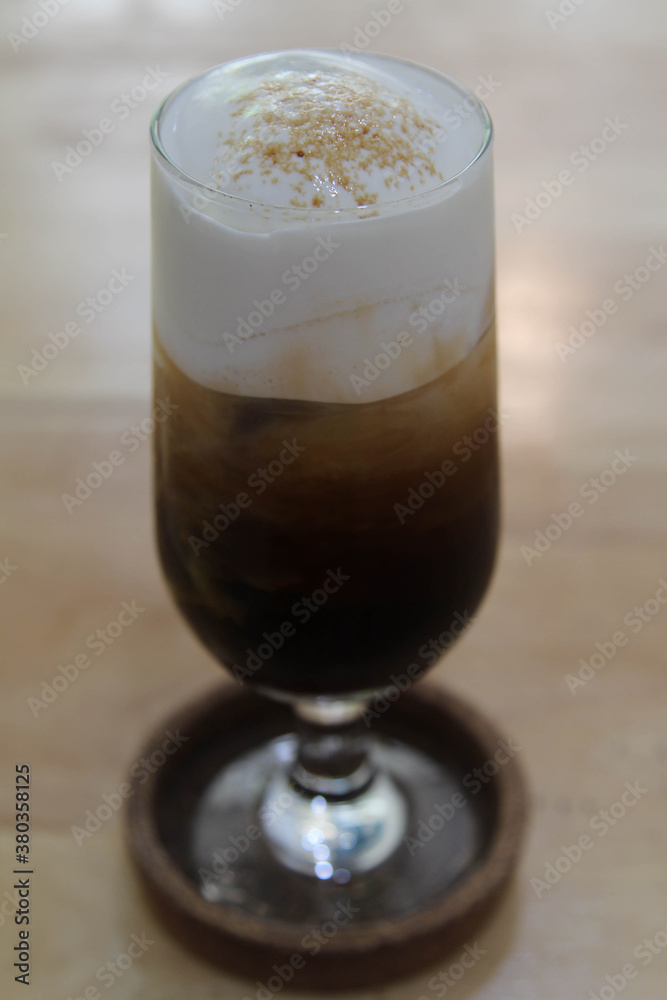 Iced coffee in a tall glass on wooden table. Iced coffee in a tall glass on wooden table.