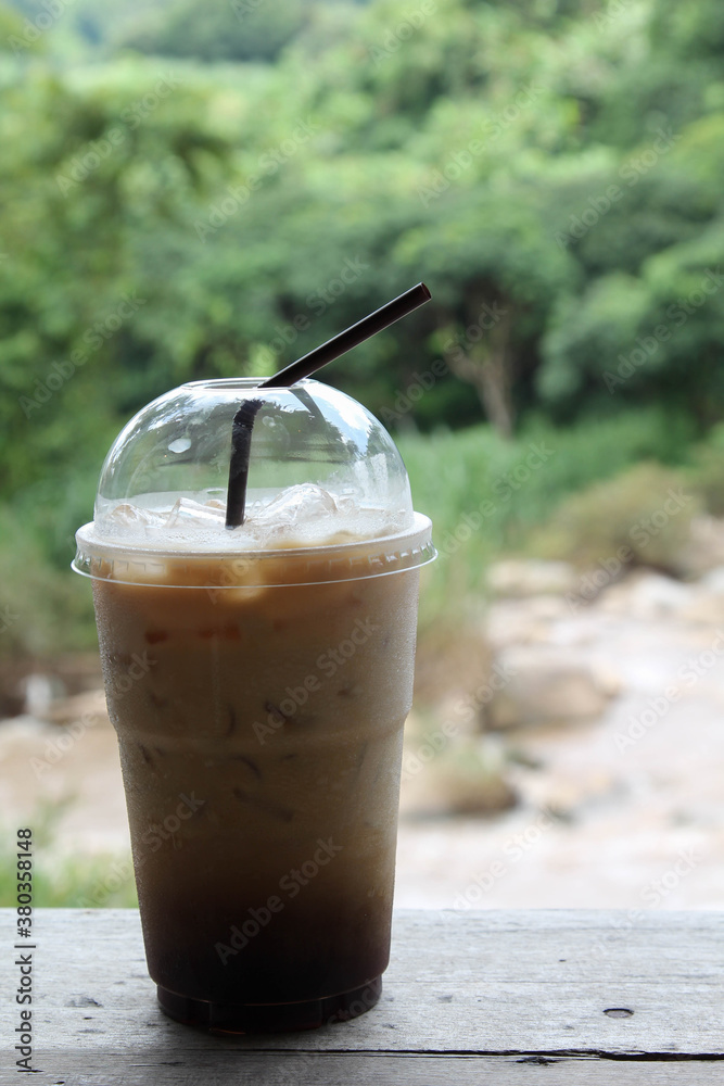 Iced coffee in a plastic cup on wooden table. Iced coffee in a plastic cup on wooden table.