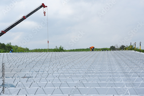 Construction worker wearing safety harness and safety uniform working at height instrallation equipment material roof on new warehouse at construction site factory project