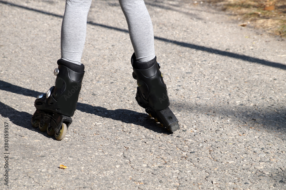 childrens feet in roller skates standing uncertainly on the road, rear view childrens feet in roller skates standing uncertainly on the road, rear view