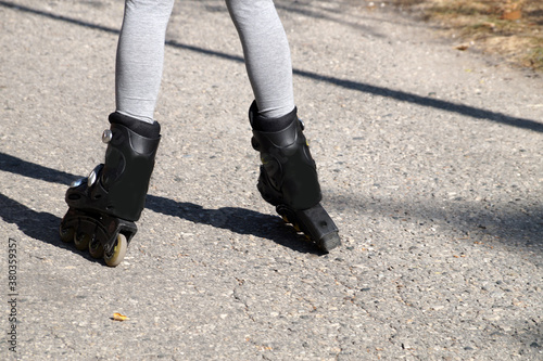 childrens feet in roller skates standing uncertainly on the road, rear view