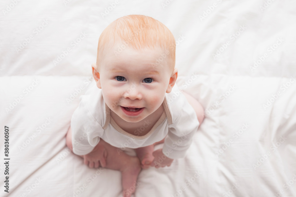 Directly above portrait of baby boy (18-23 months) sitting on duvet and looking at camera Directly above portrait of baby boy (18-23 months) sitting on duvet and looking at camera