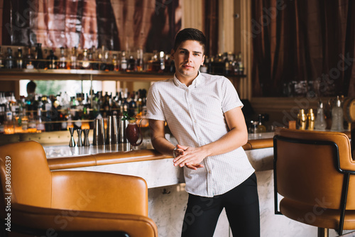 Young man standing at bar while waiting for meeting