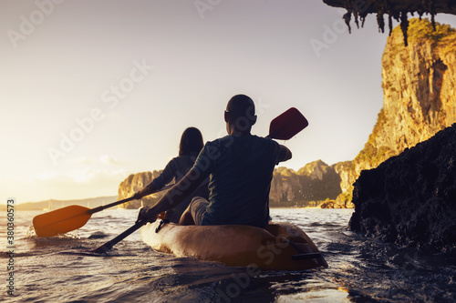 Active couple walks by canoe at sunset sea