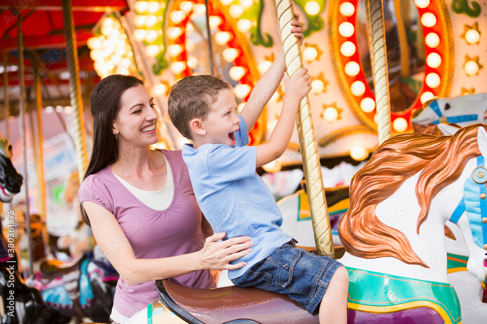 Mother and son (4-5) on carousel in amusement park Mother and son (4-5) on carousel in amusement park