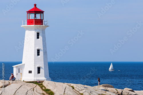 Peggy's Point Lighthouse against sea with lone sailboat