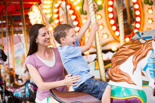 Mother and son (4-5) on carousel in amusement park photo