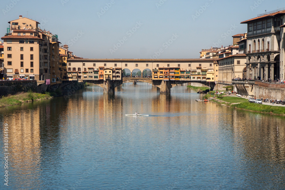 Florence, Italy: Ponte Vecchio over the Arno river on a sunny day; a rowing boat in front of the bridge