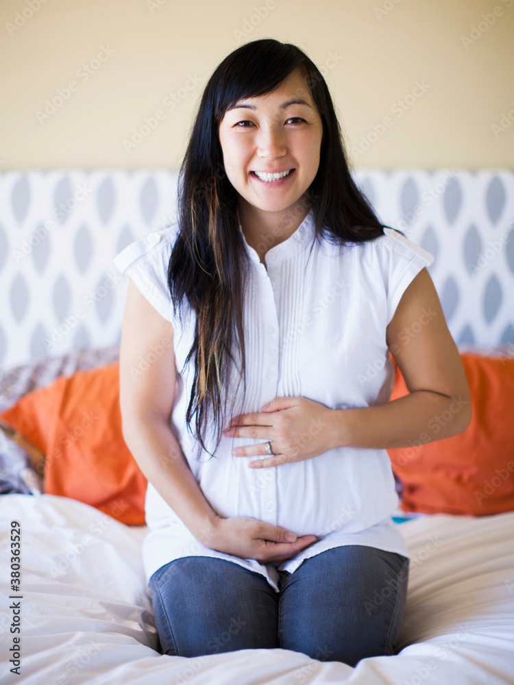 Portrait of pregnant woman sitting on bed Portrait of pregnant woman sitting on bed