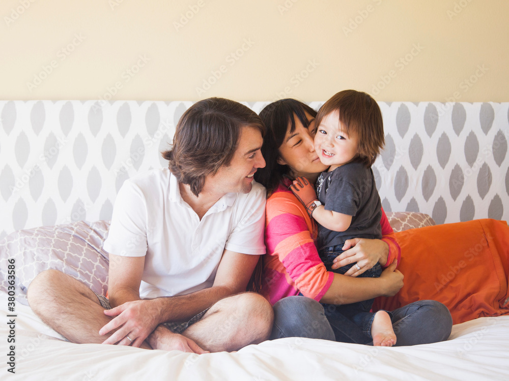 Portrait of couple sitting on bed with son (2-3) Portrait of couple sitting on bed with son (2-3)