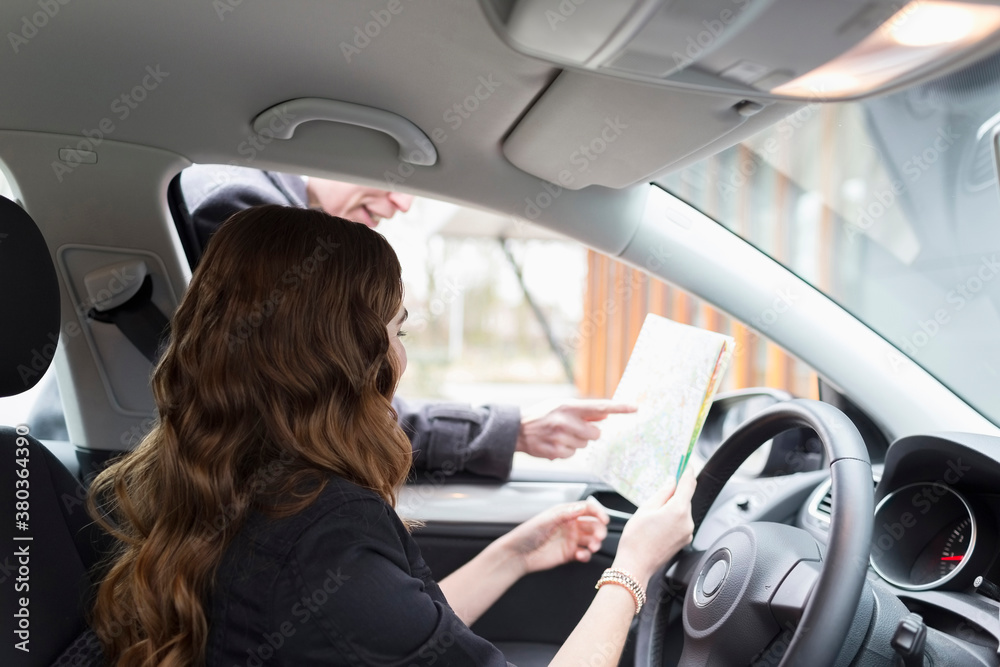 Man giving directions to young woman in car Man giving directions to young woman in car