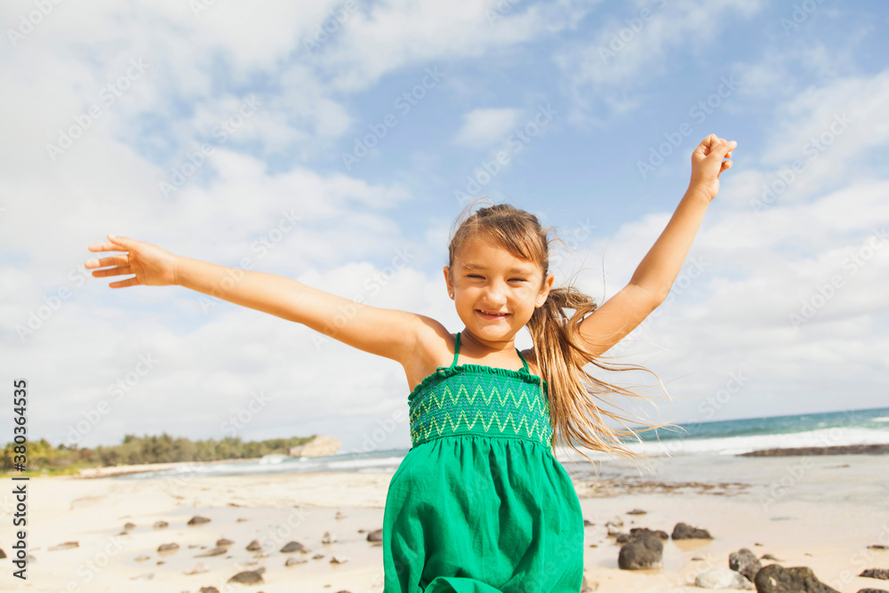 Portrait of girl (6-7) standing on beach with arms raised