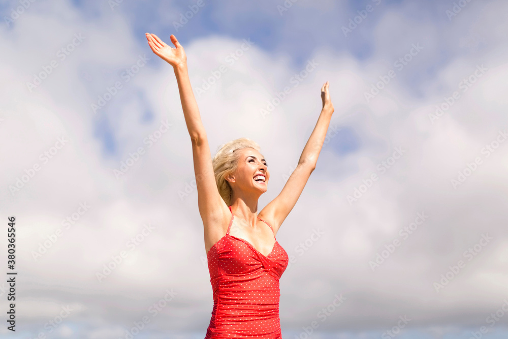 Woman wearing red one piece swimsuit rising arms and smiling Woman wearing red one piece swimsuit rising arms and smiling