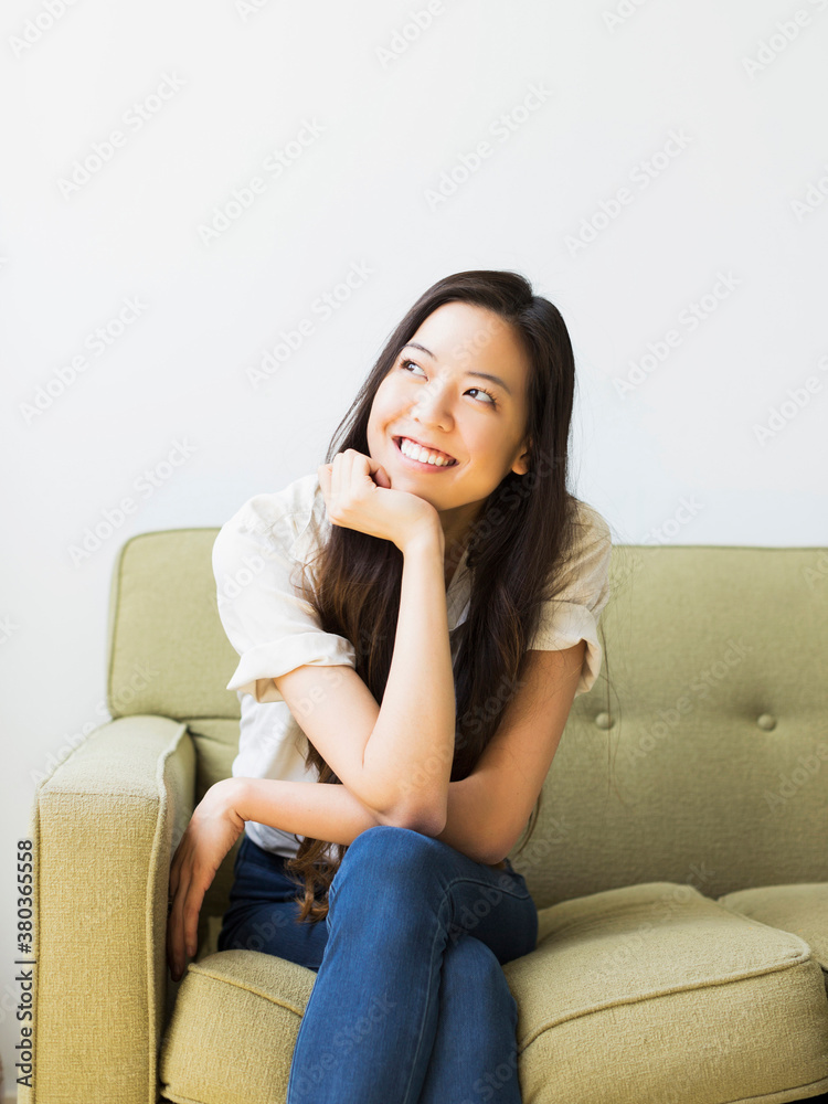Happy young woman sitting on sofa Happy young woman sitting on sofa