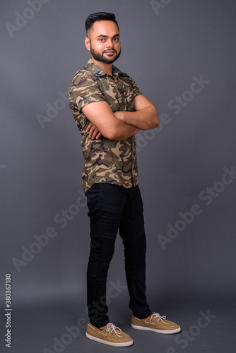 Young bearded Indian man against gray background