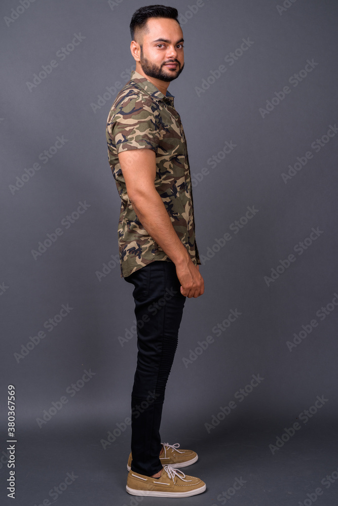 Young bearded Indian man against gray background Young bearded Indian man against gray background