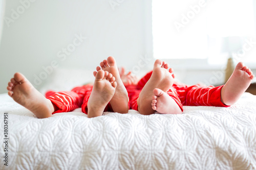 Siblings (2-3, 4-5) in red pajamas lying on bed photo